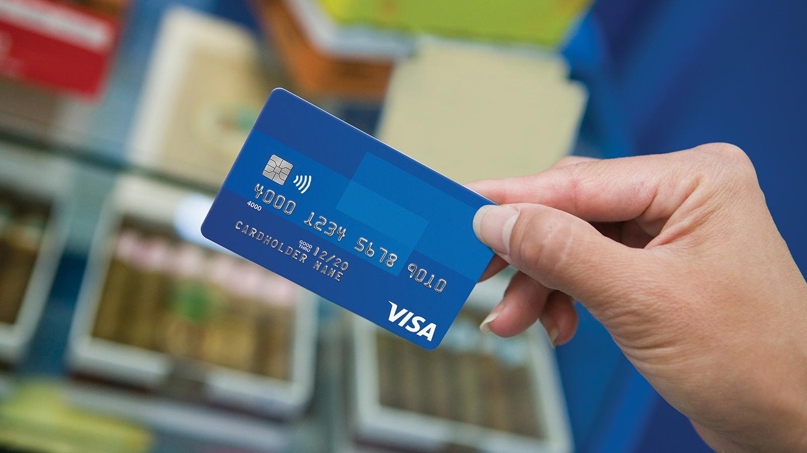 A close-up of a hand holding a Visa card.