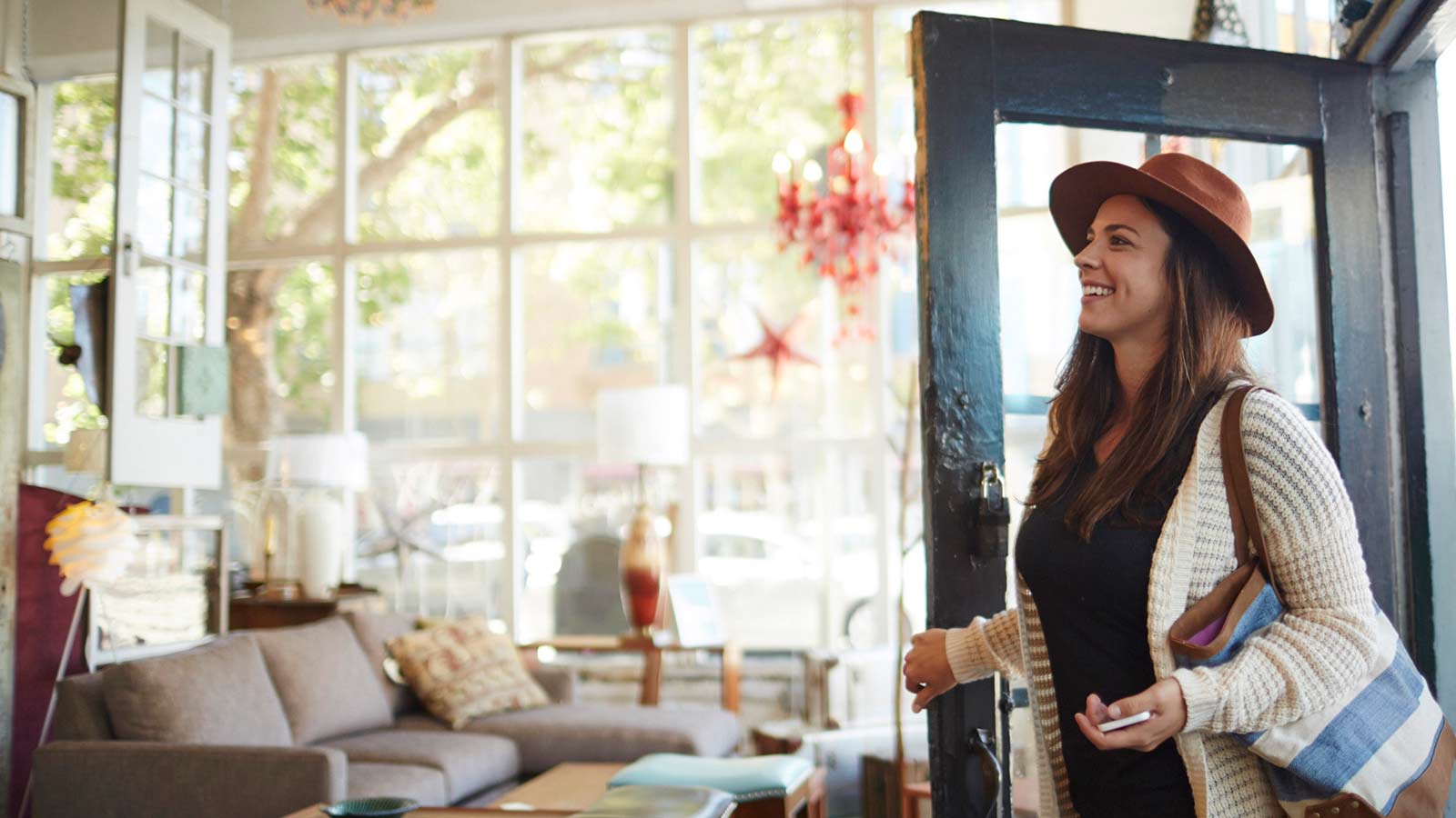 Woman entering store with smartphone in hand.