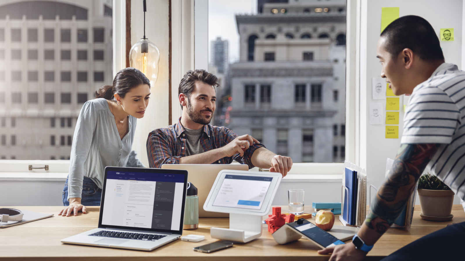 People around a desk with laptops and tablets open.