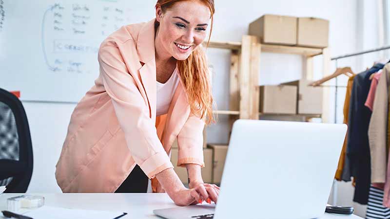 A young, female worker uses her laptop at her desk.